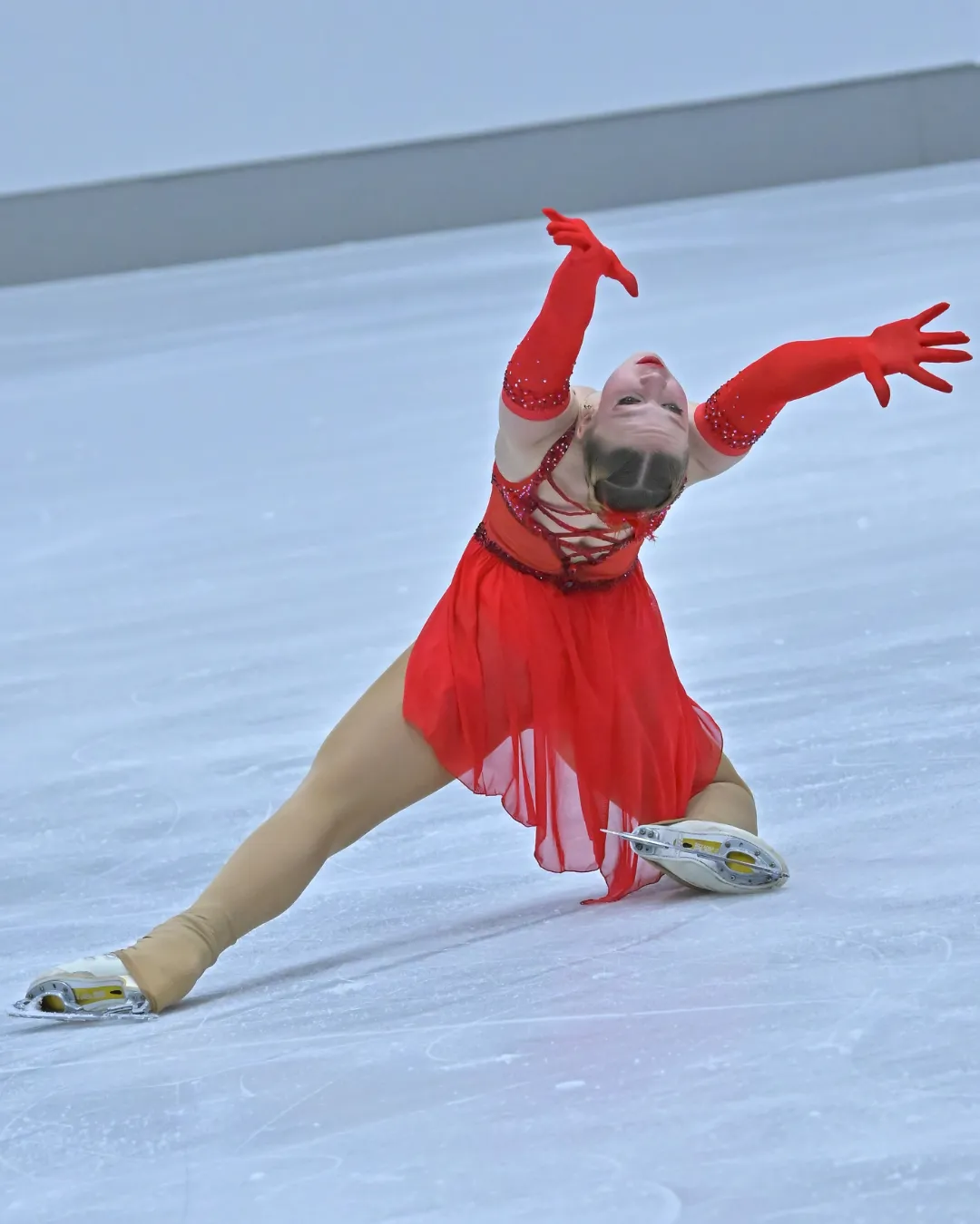 Eiskunstläuferin im roten Kleid bei einer Pirouette auf dem Eis
