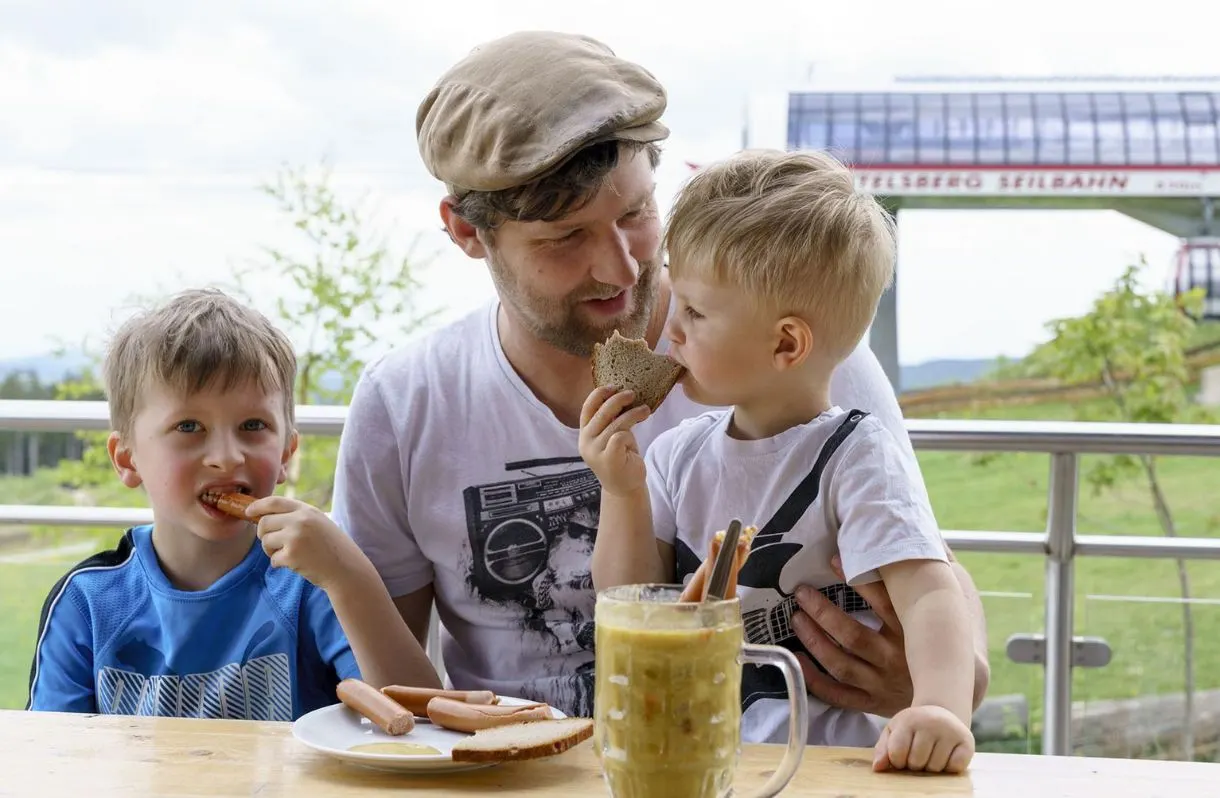 Vater mit zwei kleinen Söhnen beim Essen an der Ettelsberg-Seilbahn