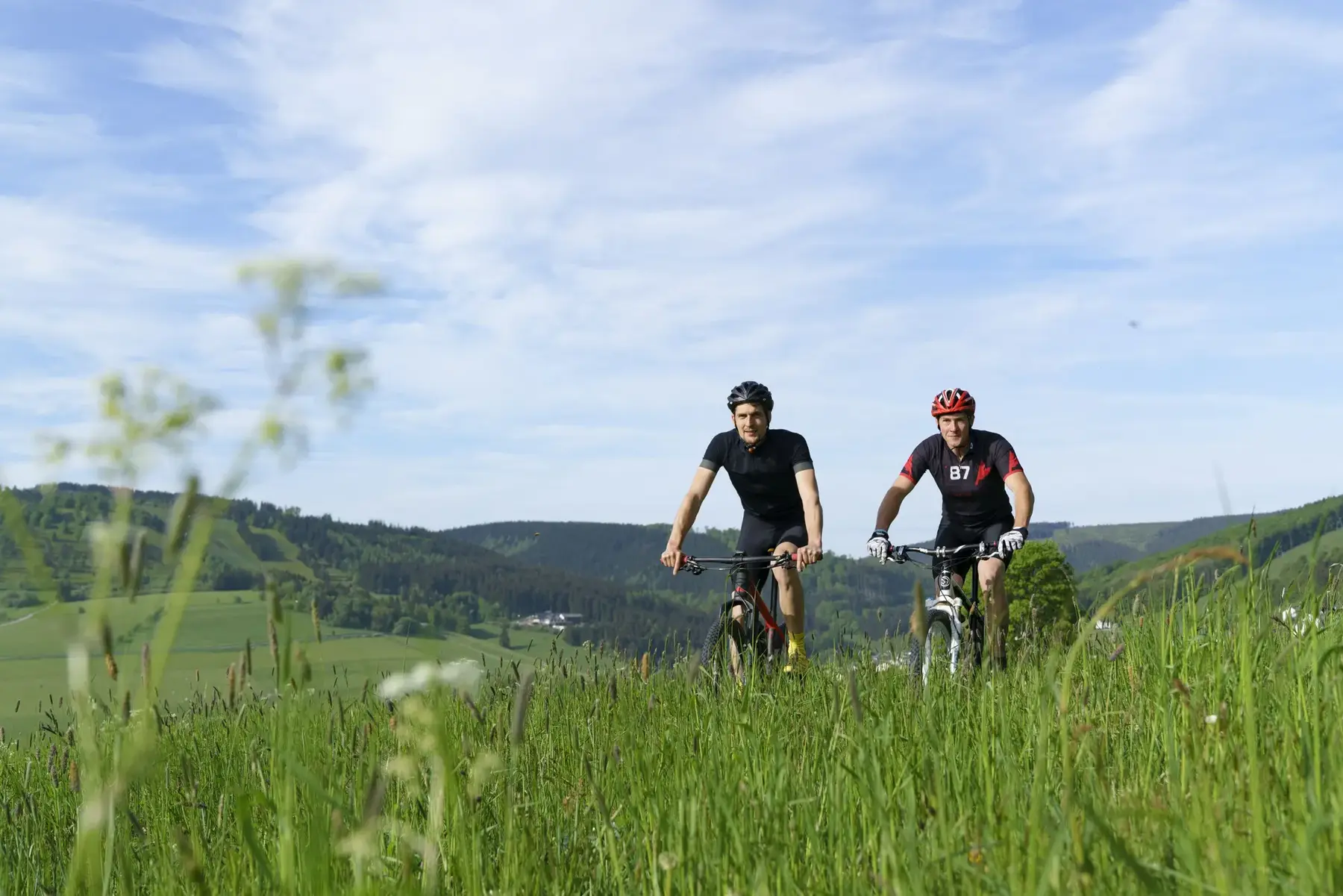 Zwei Mountainbiker auf einem Weg durch Wiesen im Upland