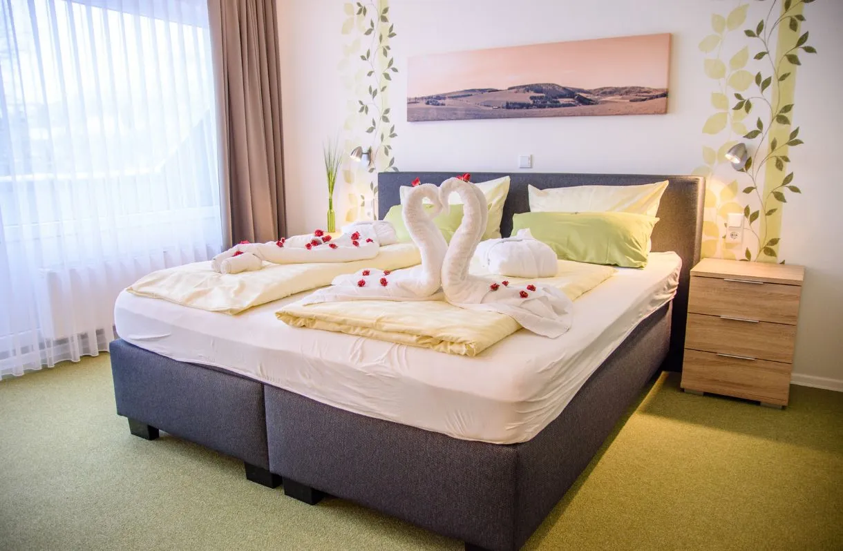 Doppelzimmer mit Handtuch-Schwänen auf dem Bett